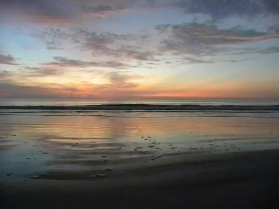 Sunrise over the water at Crescent Beach, the wet sand reflecting the sky
